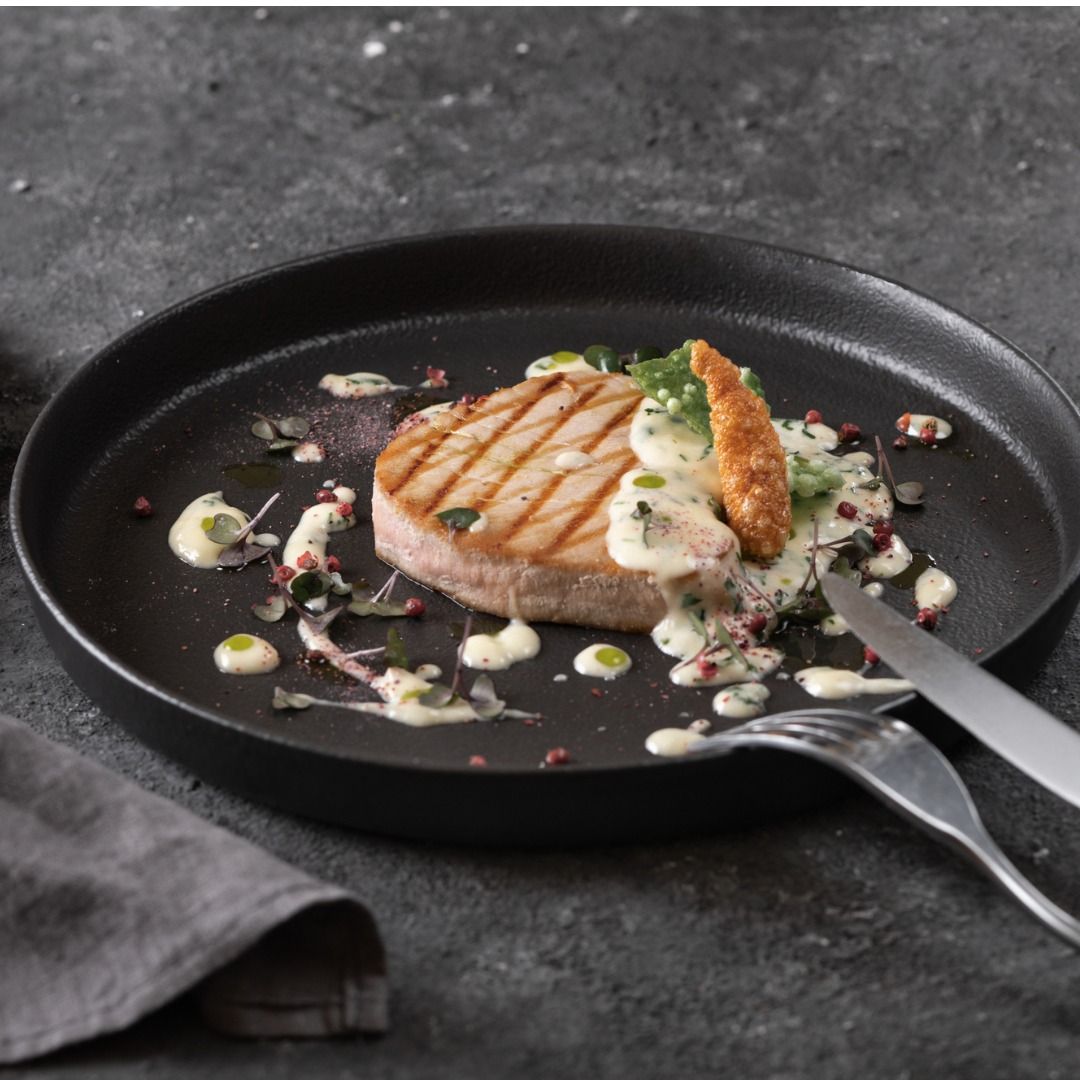 grilled-tuna-steak-with-sauce-black-round-plate-on-dark-background-picture-id1368961472.jpg