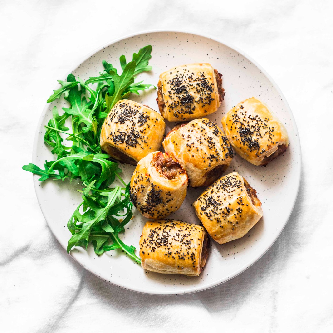 Minced-puff-pastry-rolls-and-rocket-salad---delicious-snacks,-tapas,-breakfast-on-light-background,-top-view.-Sausage-rolls-1130307407_3802x5342 square.jpg