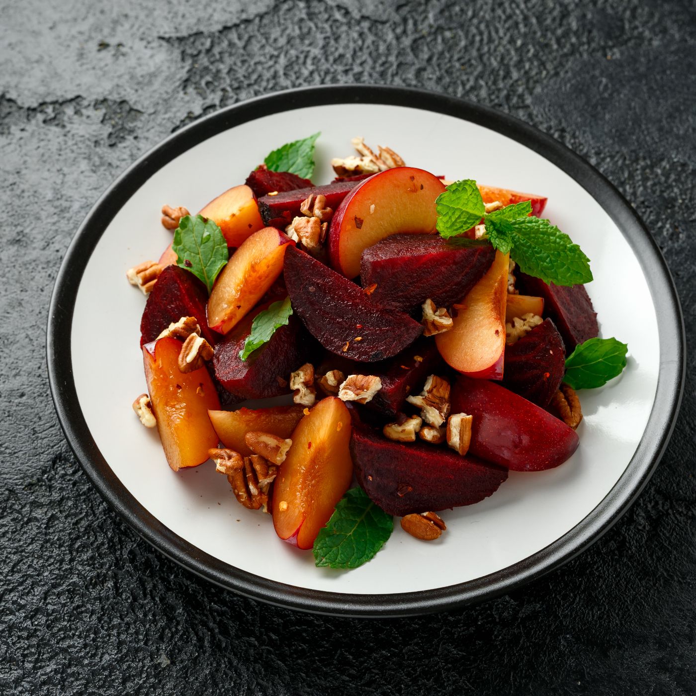 Vegan-Plum,-beet-salad-with-pecan-nuts,-mint-and-herbs-on-rustic-black-table-1239463733_5113x3409 square.jpg